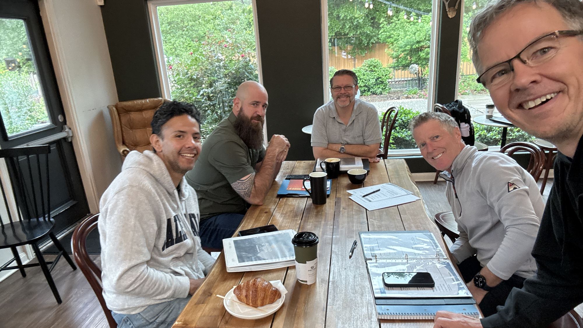 Men gathered around a wooden table at 1st Cup FORGE in The Woodlands, Texas