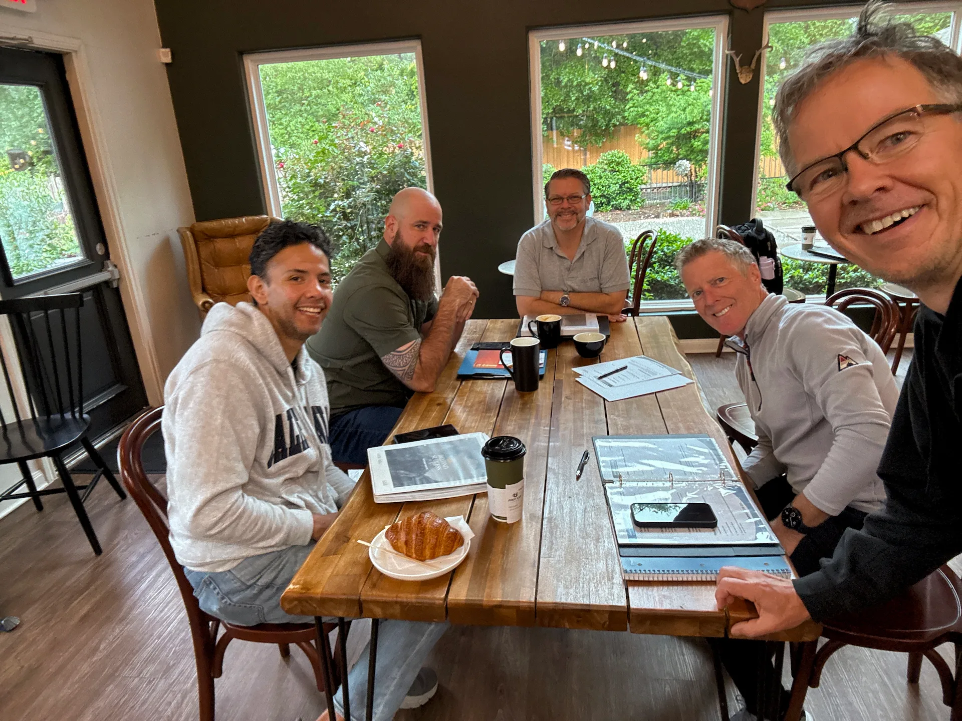 Men gathered around a wooden table at 1st Cup FORGE in The Woodlands, Texas